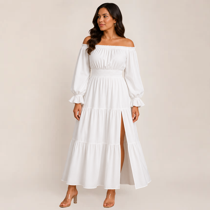 Woman posing in a relaxed flowy dress with layered details on a plain background.
