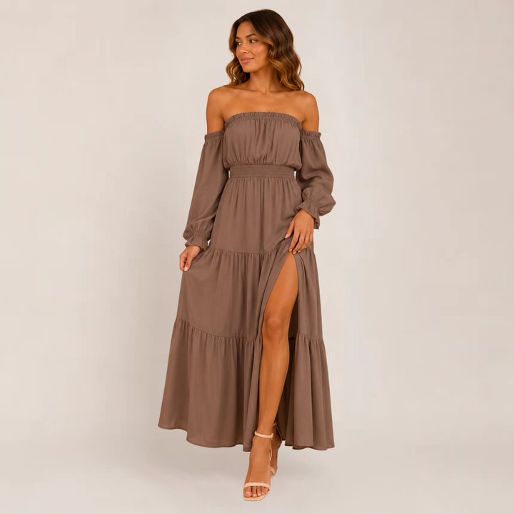 Woman posing in a flowy off-shoulder summer dress against a plain background.