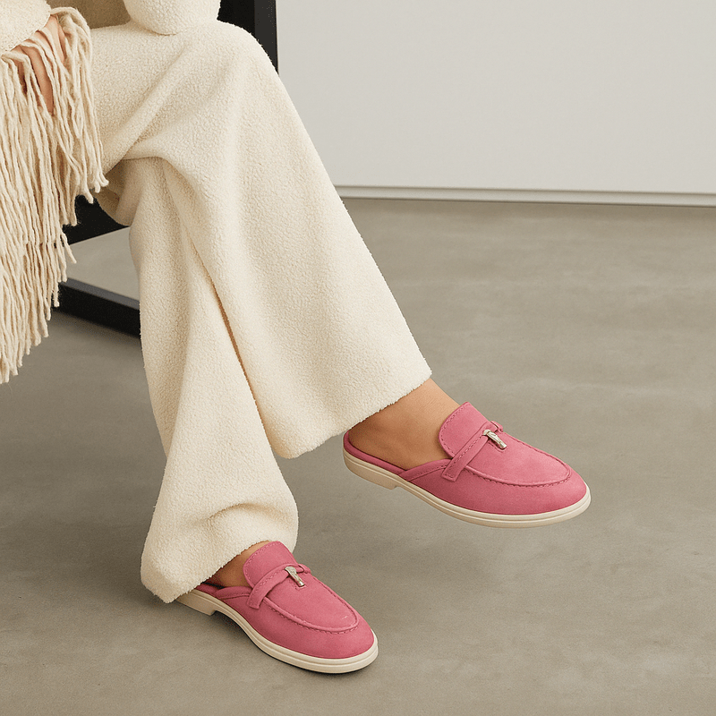Female model wearing backless mule shoes on a plain background with a clean slip-on design.