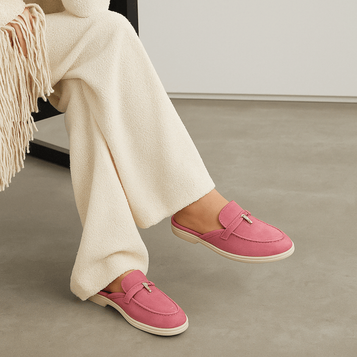 Female model wearing backless mule shoes on a plain background with a clean slip-on design.