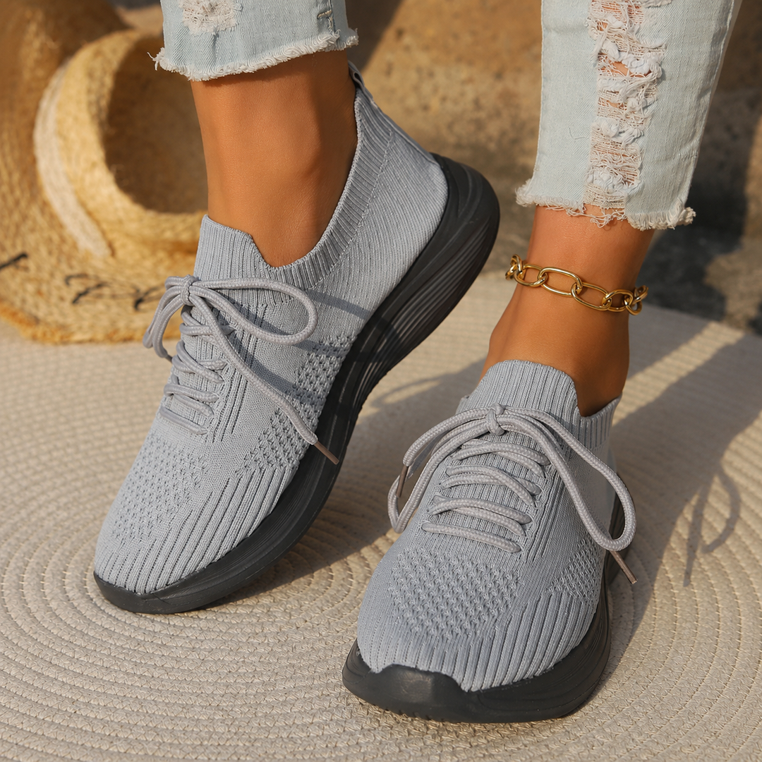 Female model wearing lightweight walking shoes against a plain background.