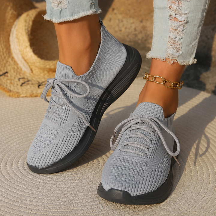 Female model wearing lightweight walking shoes against a plain background.