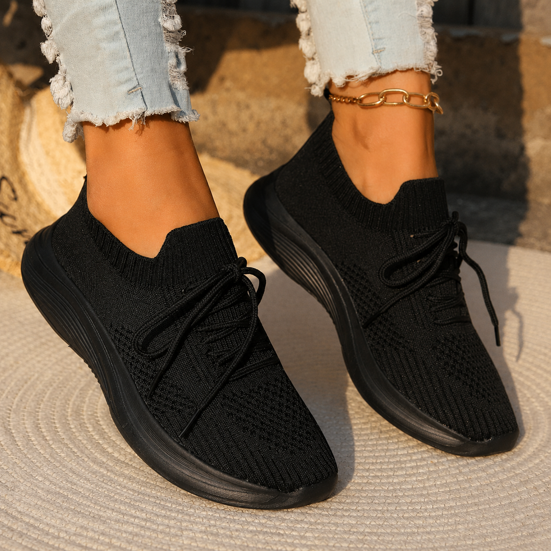 Close-up of women’s lace-up sneakers on a plain background.