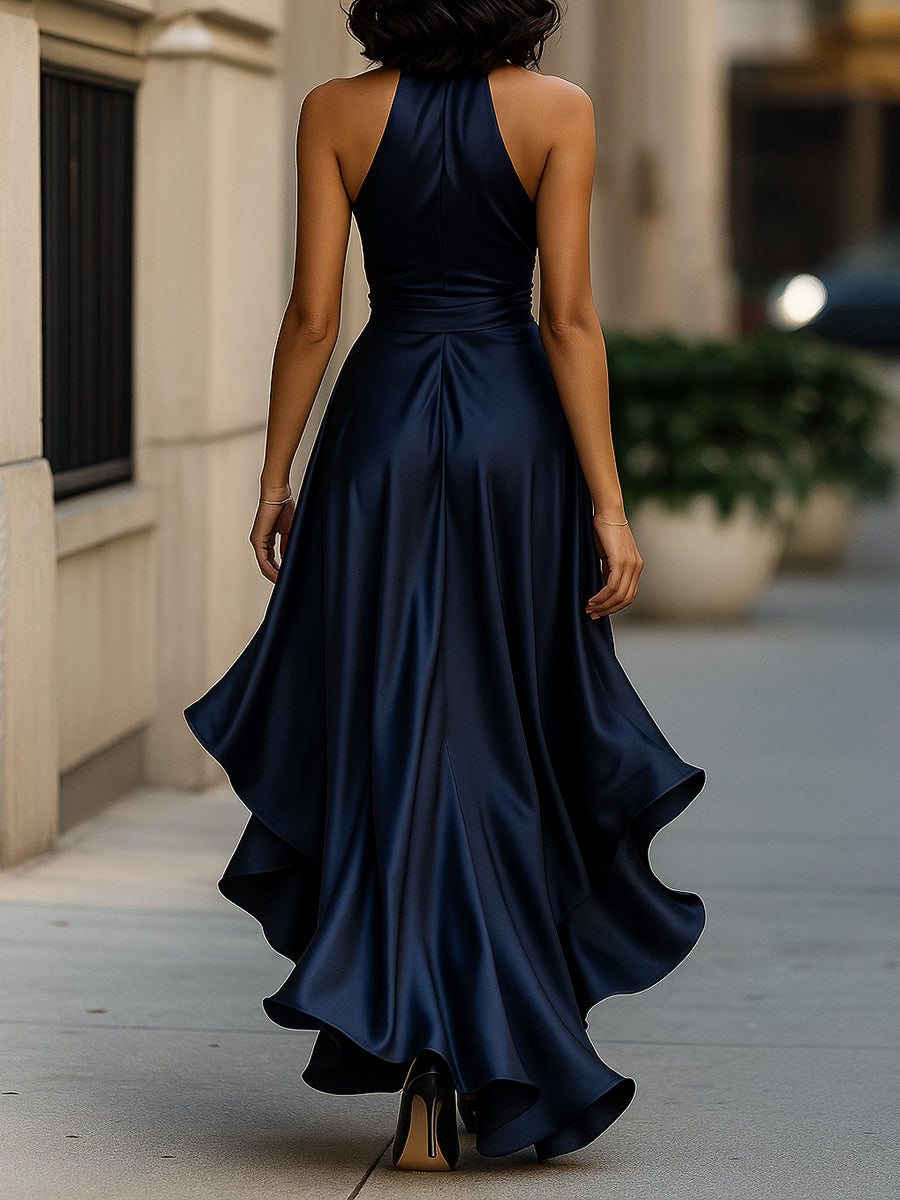 Woman in a navy evening gown with waist tie and high-low hem on a plain background.