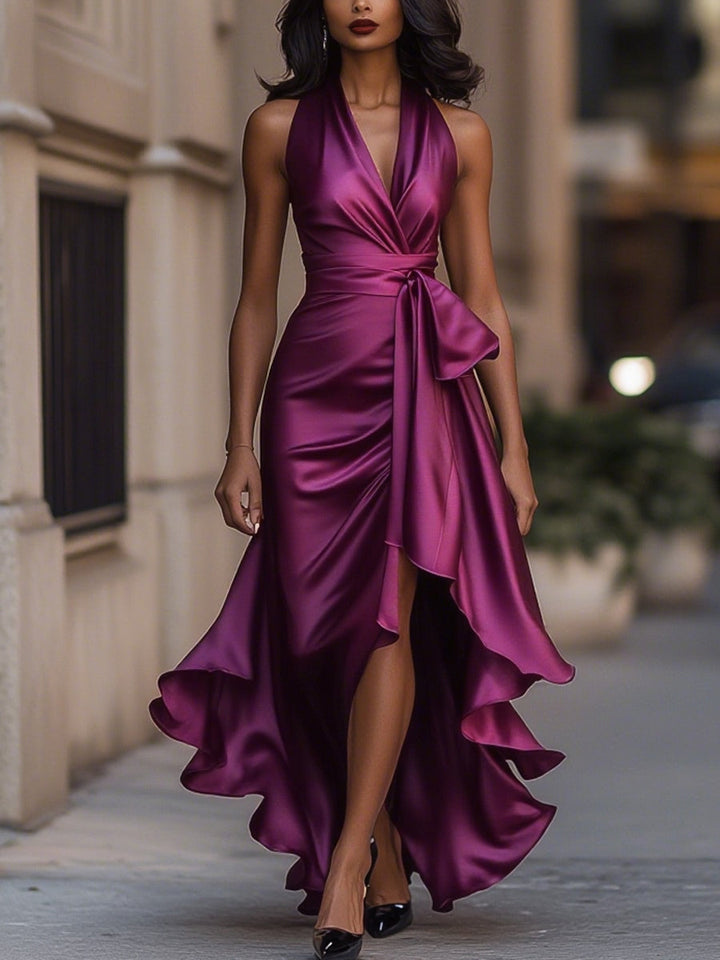 Model wearing a navy high-low gown with soft waist sash on a plain background.