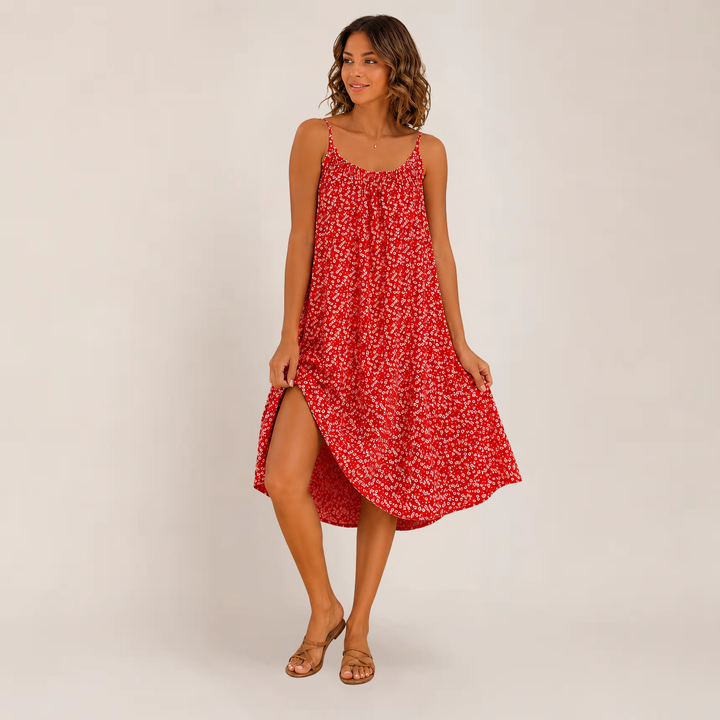 Female model in a flowy floral dress styled for warm-weather fashion on a plain background.