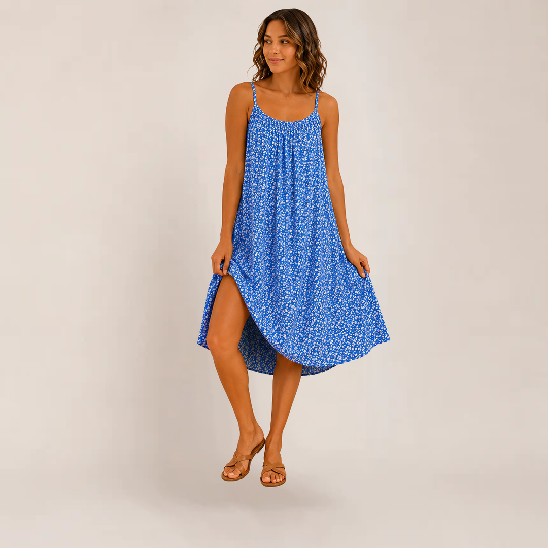 Model wearing a lightweight floral dress with thin straps and an airy summer look on a plain background.