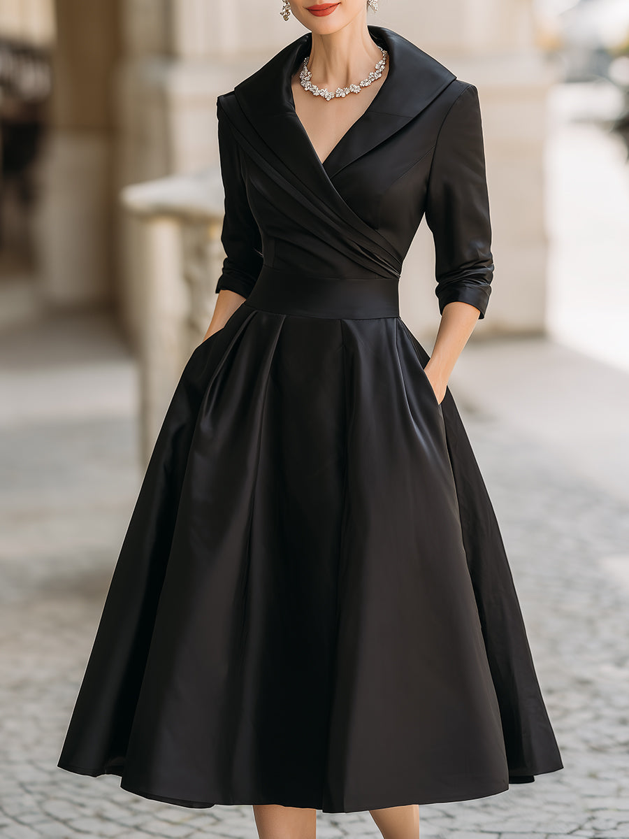 Female model wearing a graceful midi dress against a plain background with a draped neckline and long sleeves.