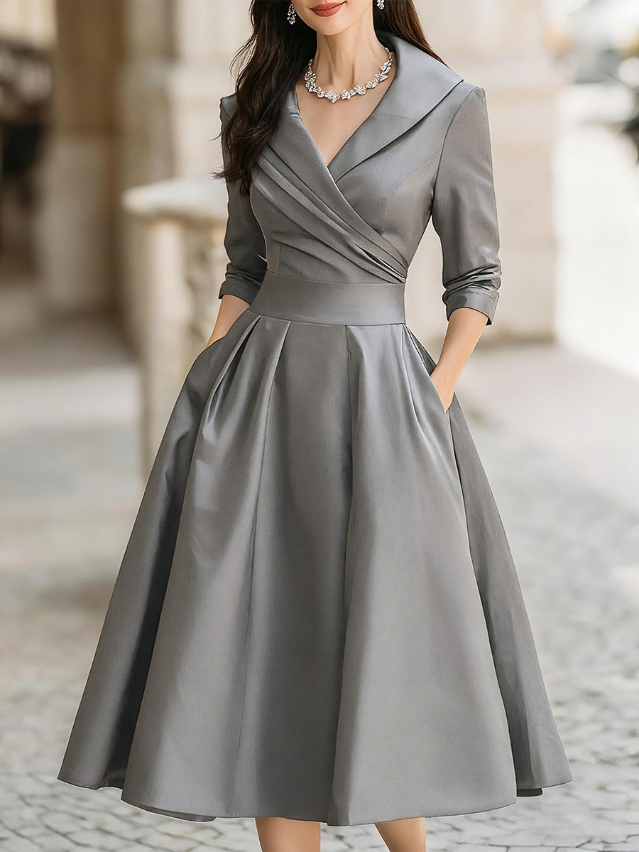 Woman wearing a classic long sleeve midi dress on a plain background.