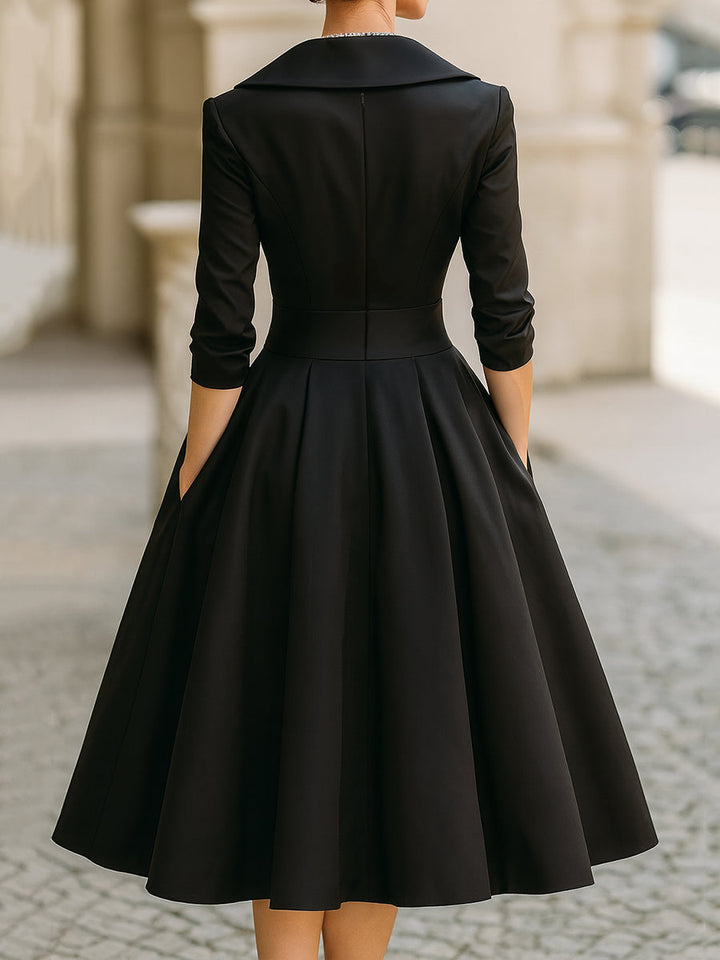 Woman in a refined midi dress on a plain background showing a defined waist and flowing skirt.