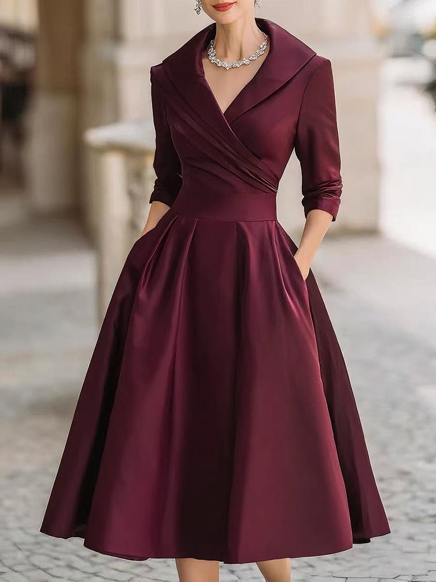 Female model in a long sleeve midi dress with a soft flowing shape on a plain background.