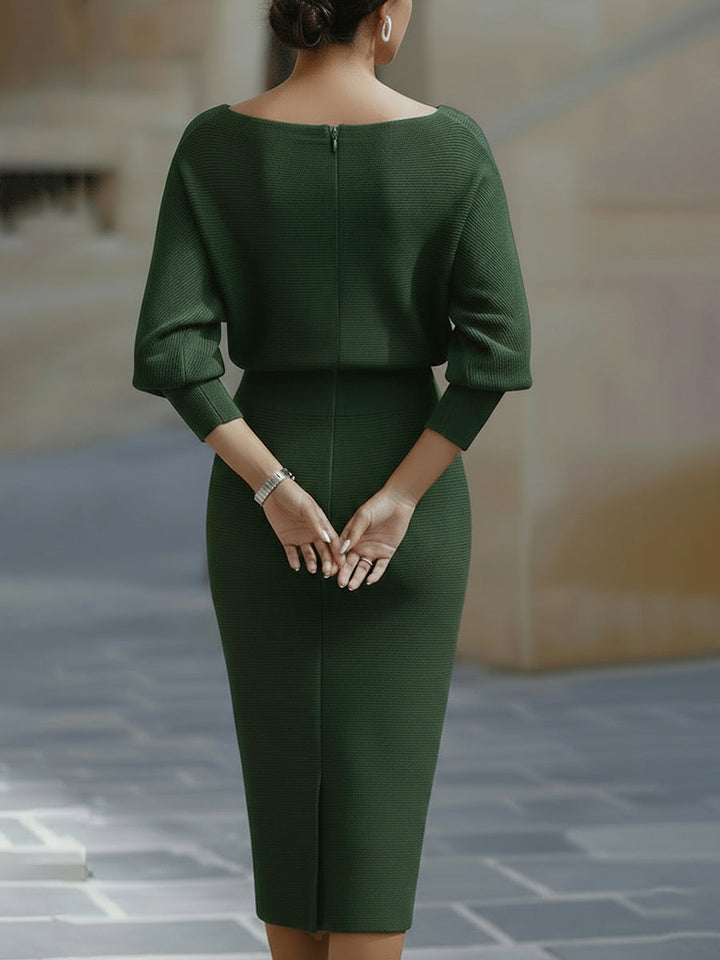 Woman in a white dress with relaxed upper shape and fitted midi skirt on a plain background.