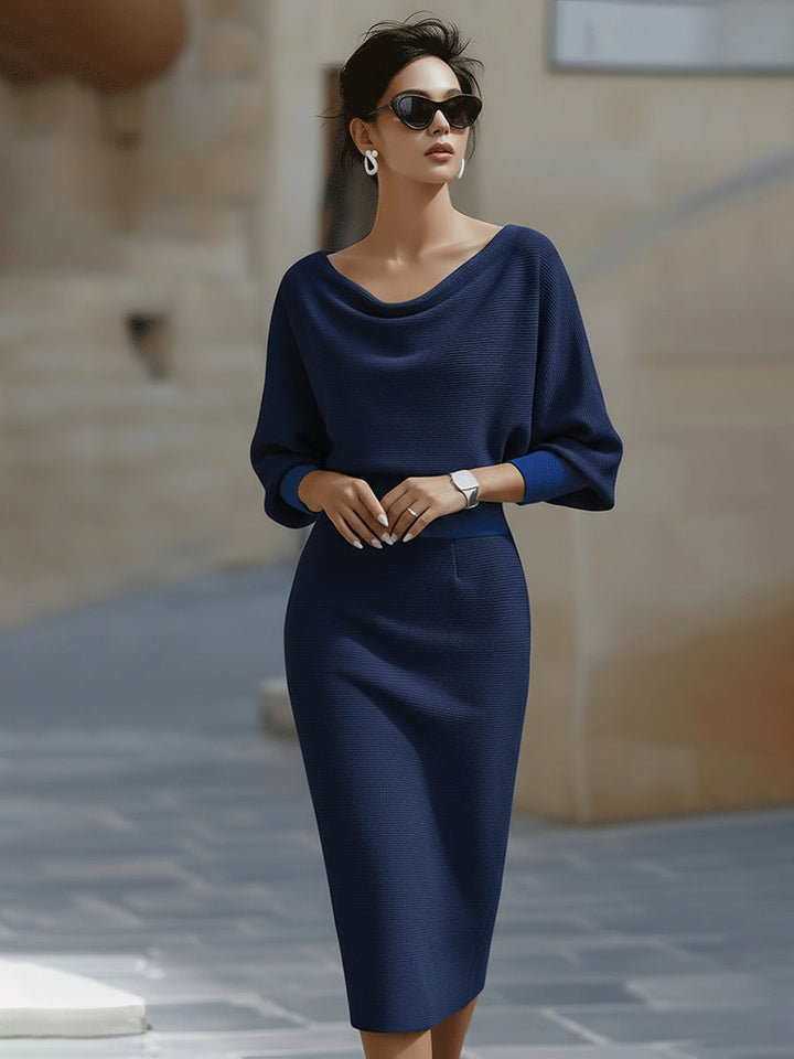 Female model wearing a white midi dress with cowl neckline and batwing sleeves on a plain background.
