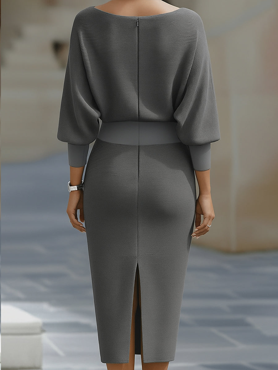 Woman wearing a white long sleeve dress with slim midi skirt on a plain background.