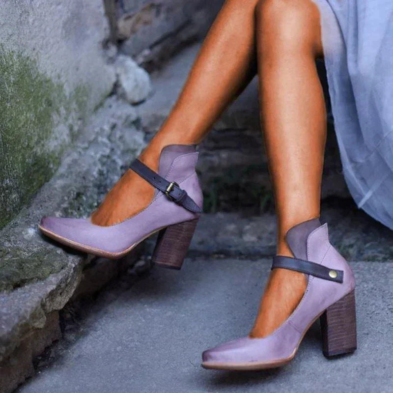 Foot wearing elegant heeled sandals on a plain background.