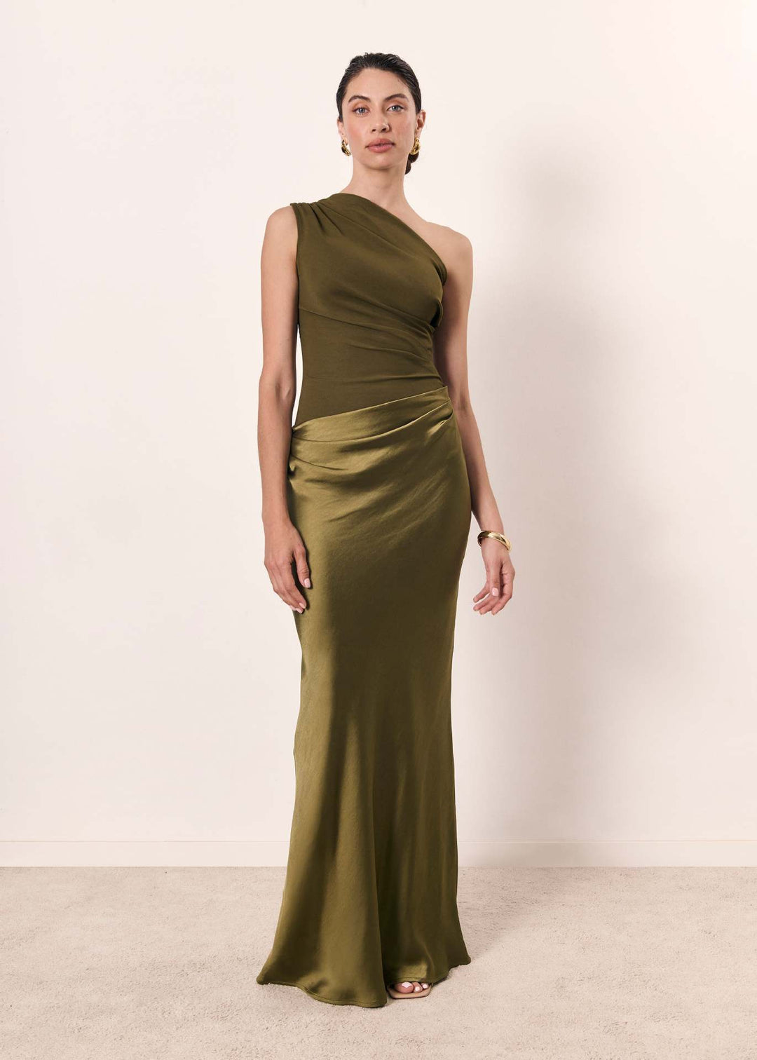 Female model showcasing a long flowing dress with a flattering waistline on a plain background.