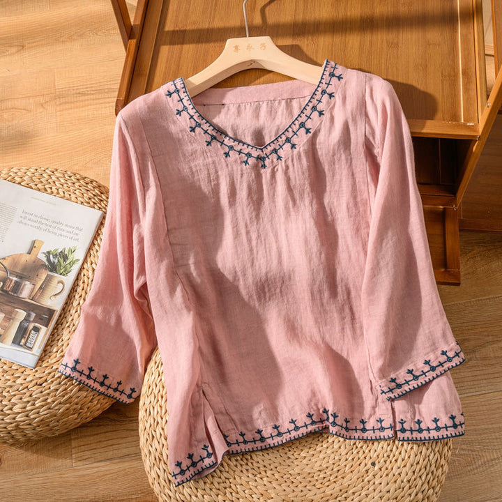 Lightweight embroidered blouse displayed on a nature furniture background with refined style.