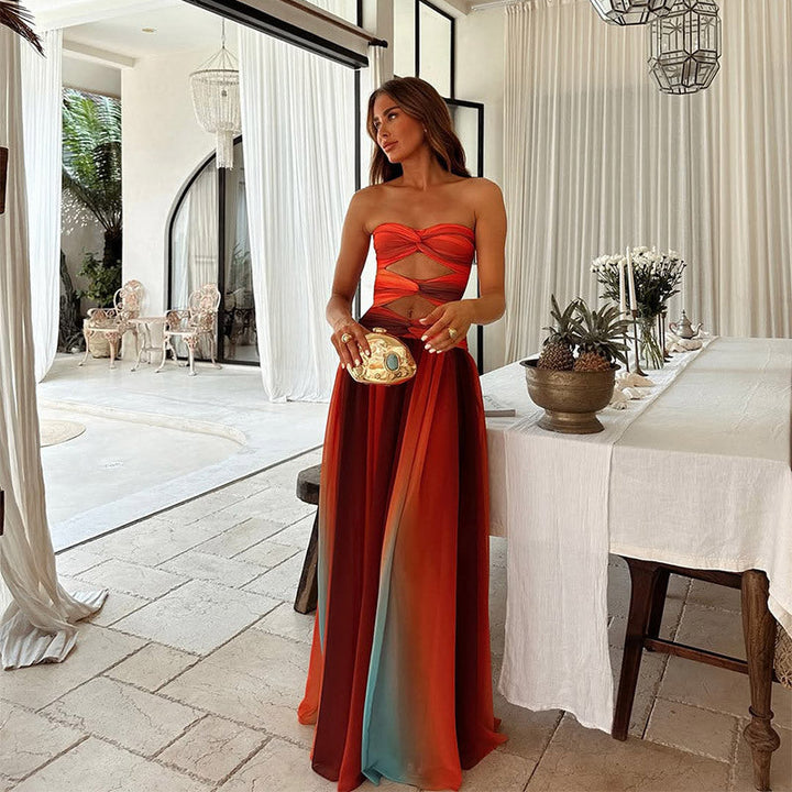 Female model wearing a tie-dye long dress with hollow-out detail on a dining area background.
