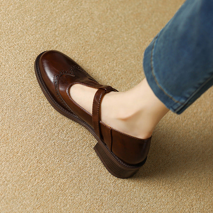 Woman standing in woven slip-on flats with strap detail on a plain background.