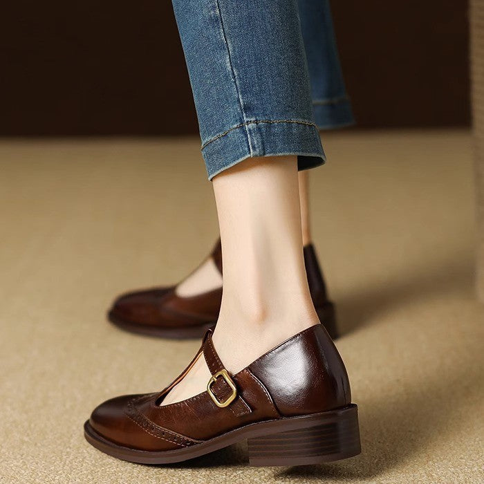 Woman styling flat woven slip-on shoes with trousers on a plain background.