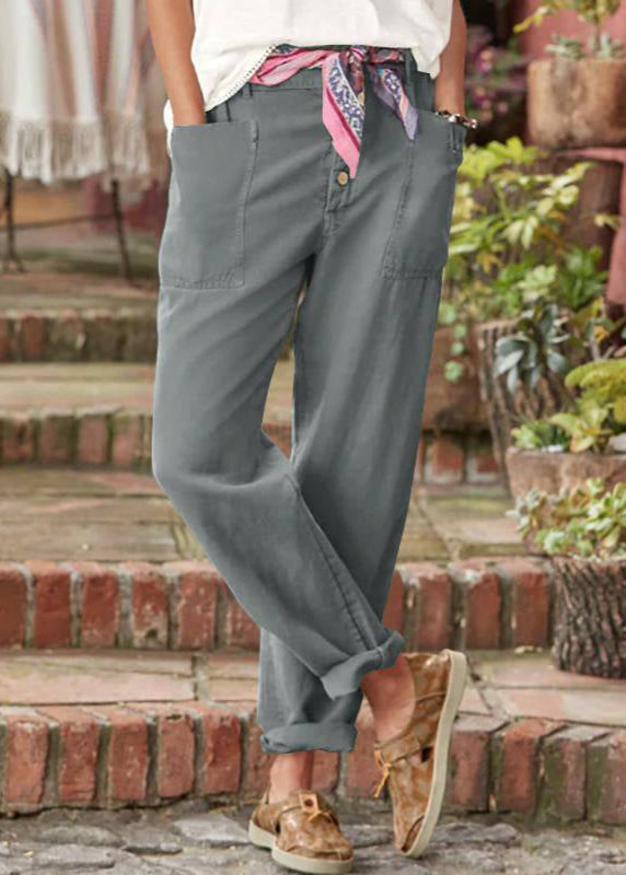 Woman in flowy tailored trousers posing on a staircase background.