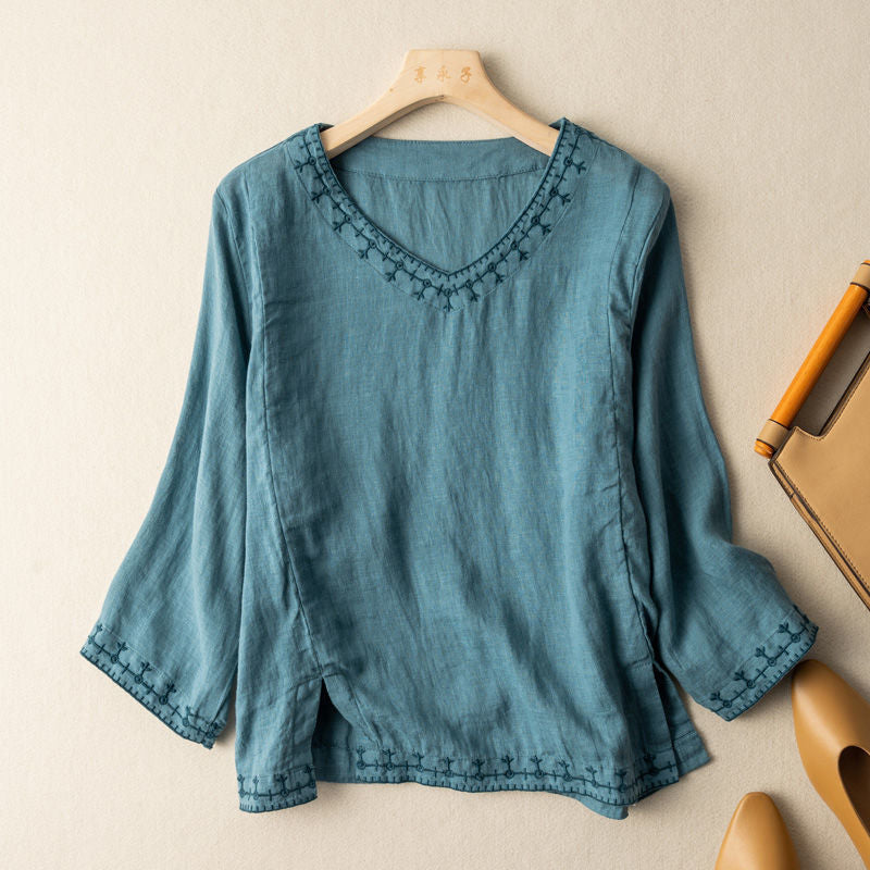 Feminine embroidered V-neck blouse on a clean background with graceful detail.