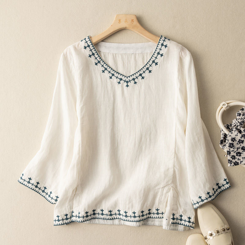 Embroidered V-neck blouse on a clean background with elegant feminine detailing.