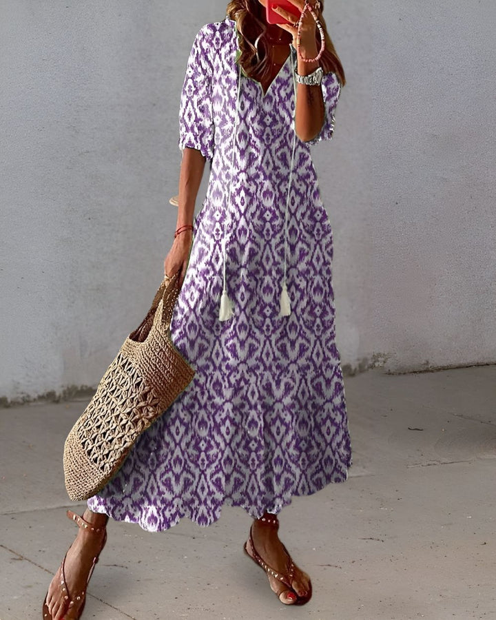 Female model showcasing a relaxed summer dress with flowing details on a plain background.