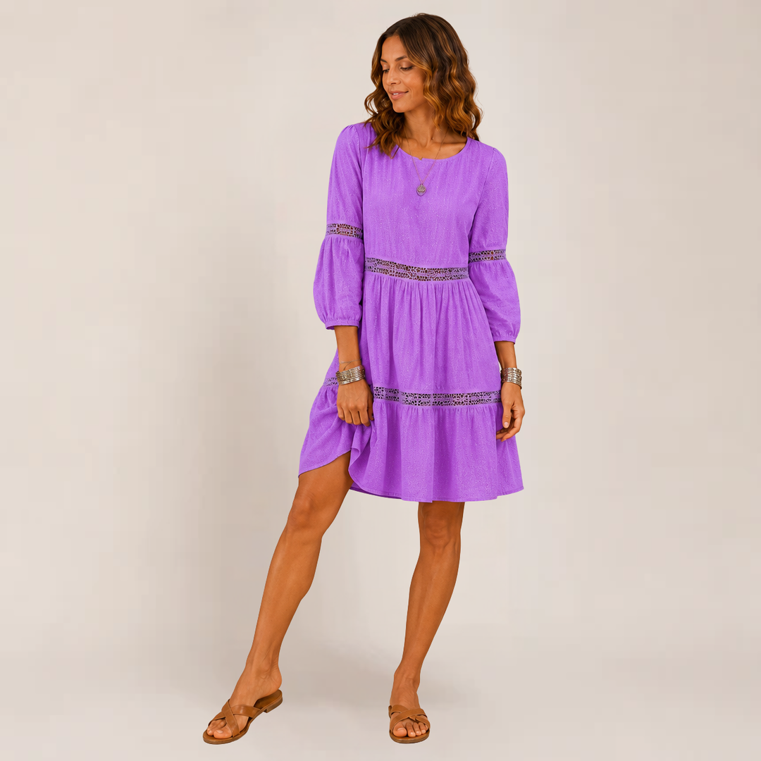 Female model wearing a flowy tiered sundress with 3/4 sleeves on a plain background.