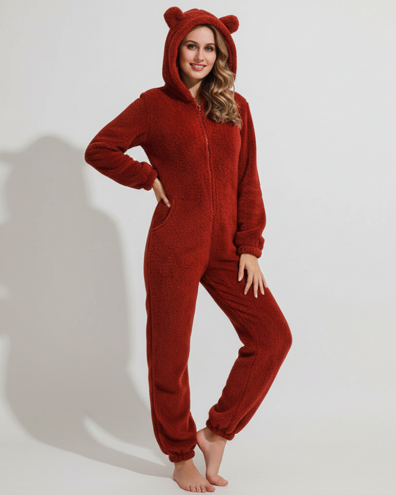  Female model in a relaxed-fit fleece jumpsuit featuring side pockets on a plain background.