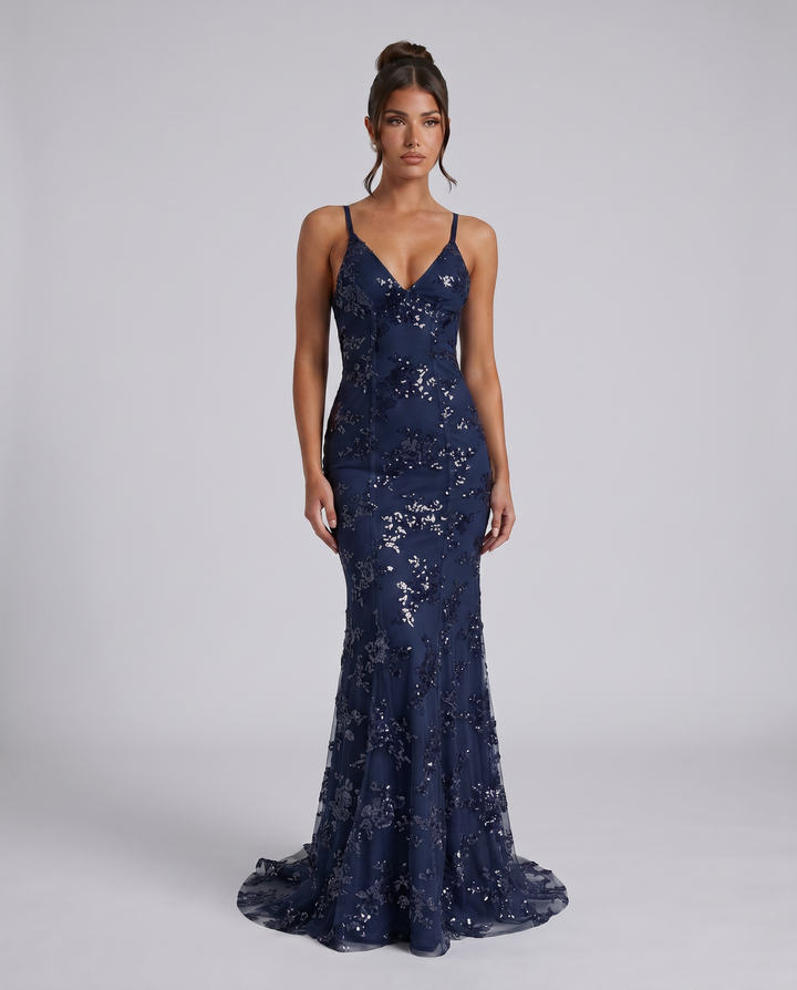 Female model in a gray sleeveless formal dress with deep V front on a plain background.