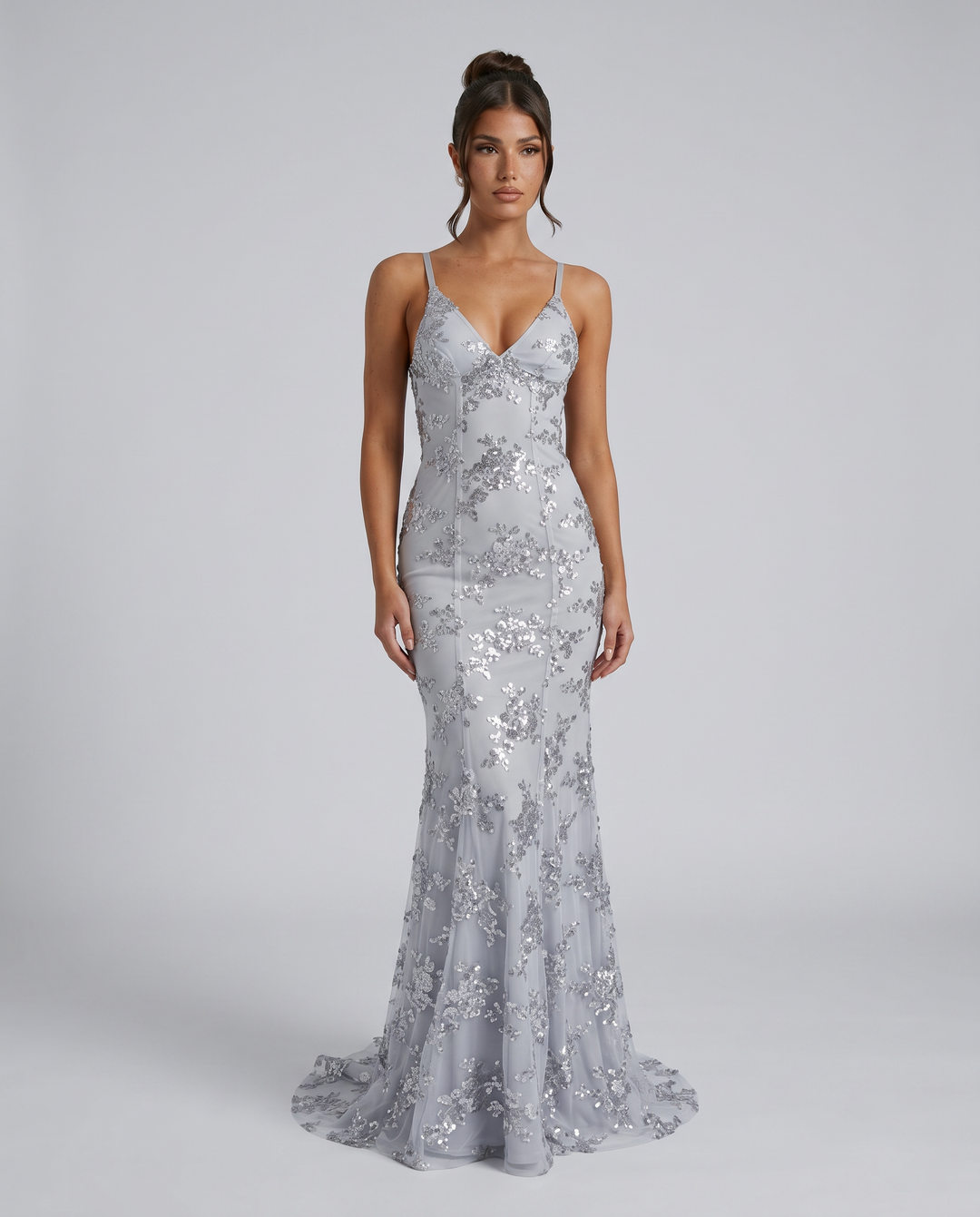 Woman wearing a gray embellished maxi dress with deep V neckline on a plain background.