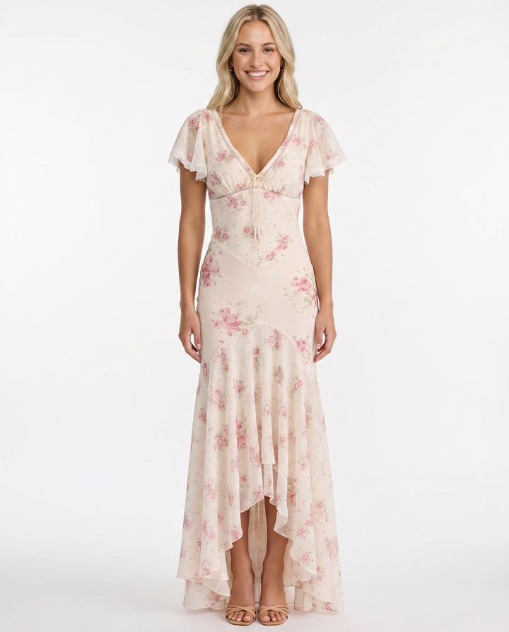 Female model in a flowing floral long dress on a plain background.