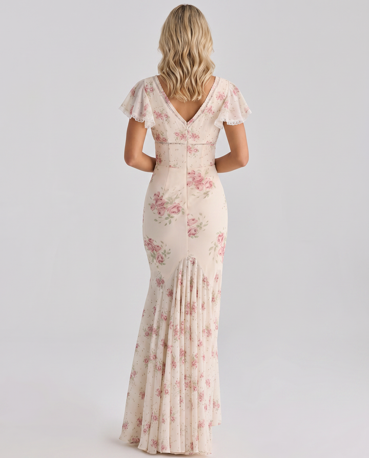 Woman in an ivory floral maxi dress standing against a plain background.