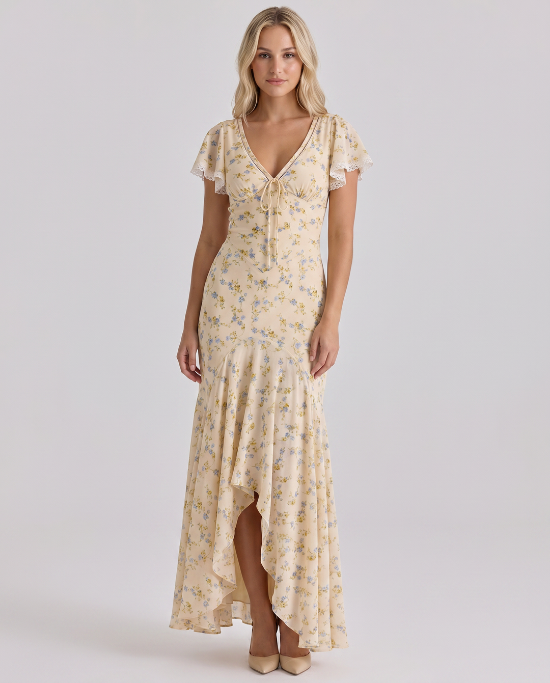 Woman in a long floral dress with cap sleeves against a plain background.