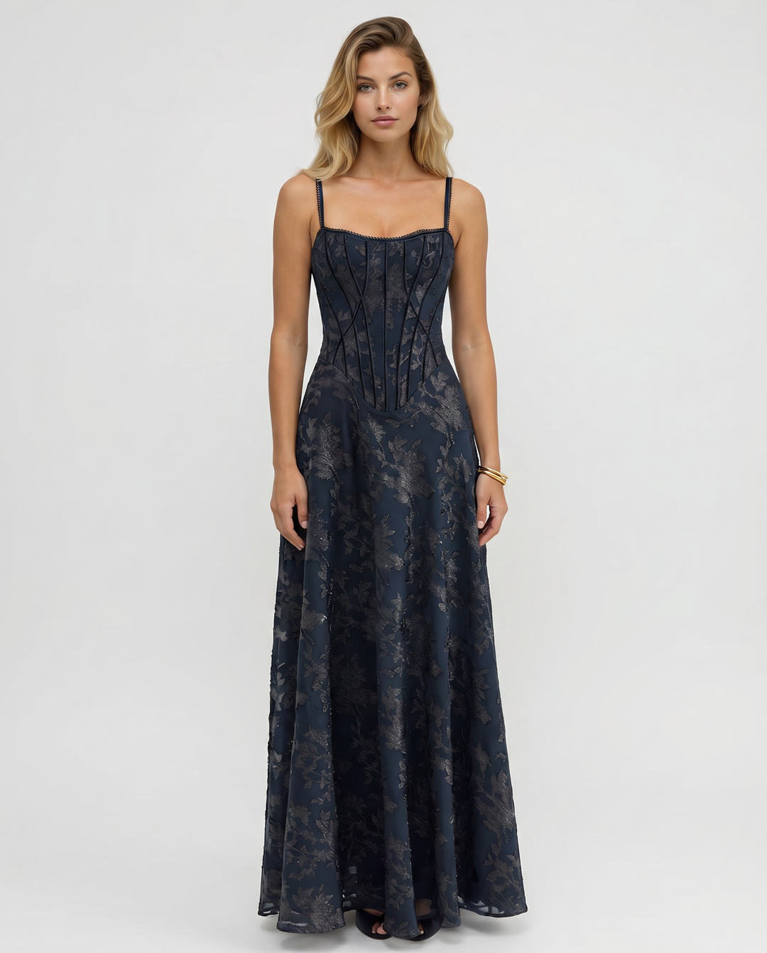 Female model wearing a navy maxi dress with slim straps against a plain background.