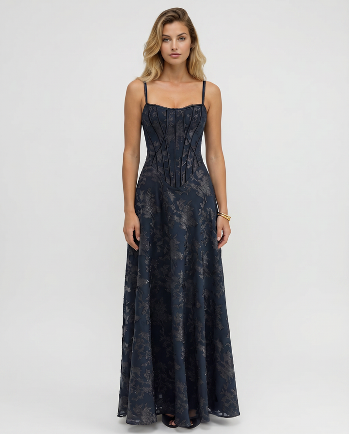 Female model wearing a navy maxi dress with slim straps against a plain background.