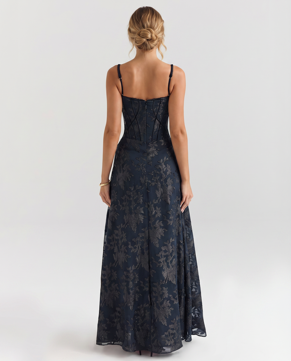 Woman in a navy full-length dress with a fitted bodice on a plain background.