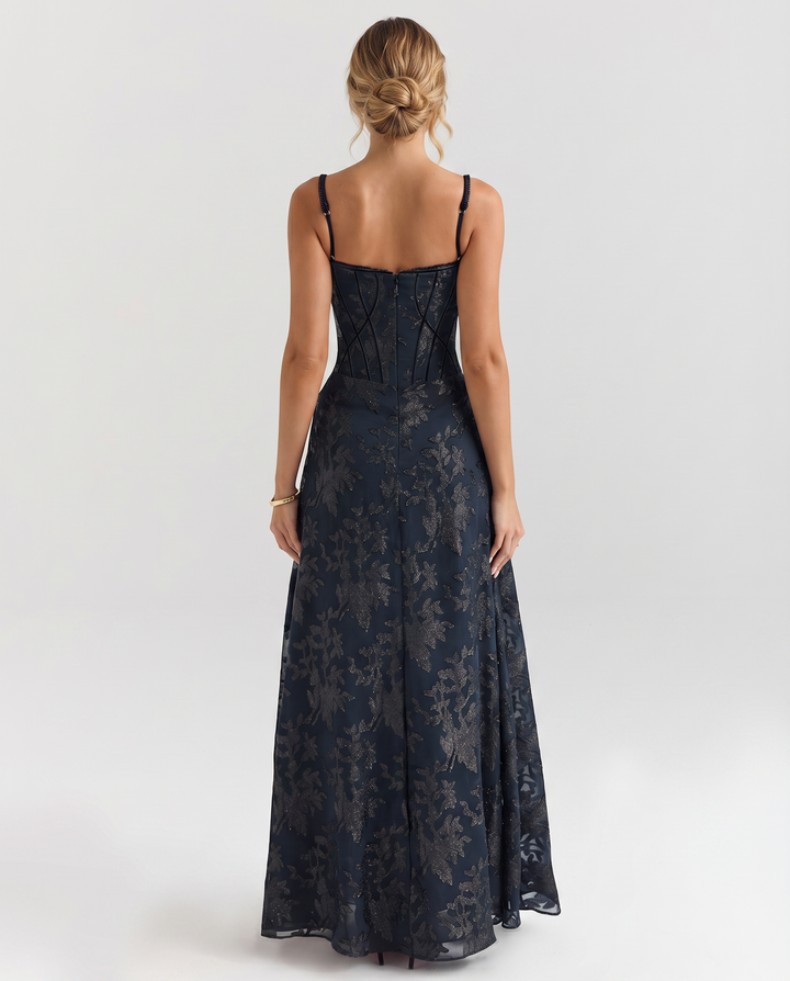 Woman in a navy full-length dress with a fitted bodice on a plain background.