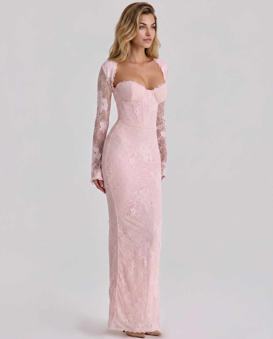 Woman dressed in a fitted long sleeve lace maxi dress on a plain background.