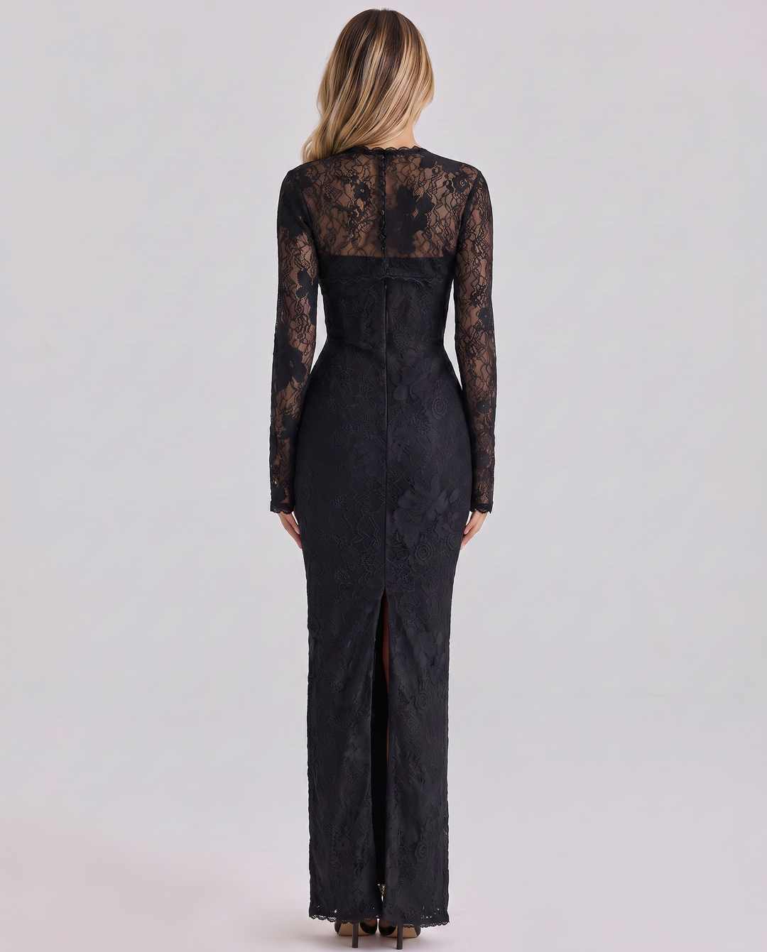 Woman in a long sleeve lace maxi dress with a smooth lined finish on a plain background.