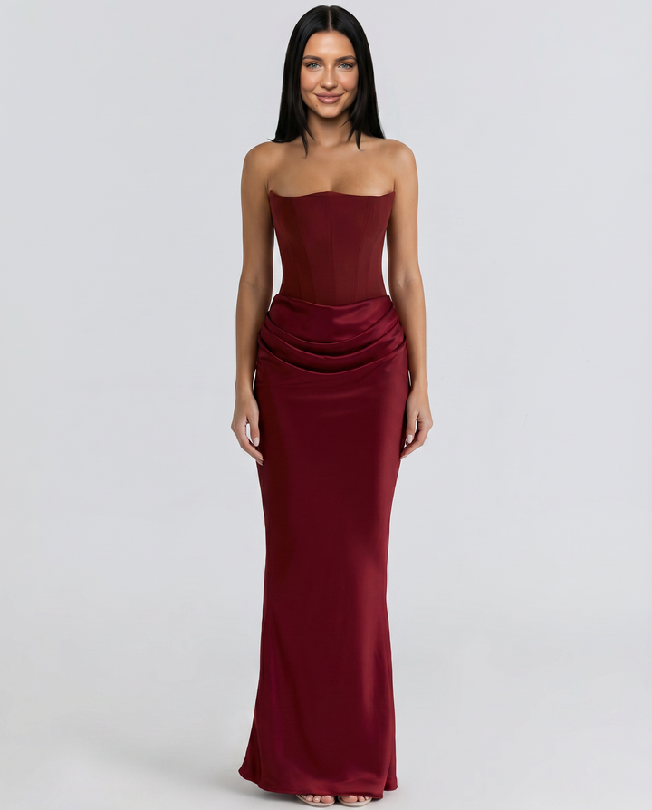 Woman in a strapless formal maxi dress standing on a plain background.