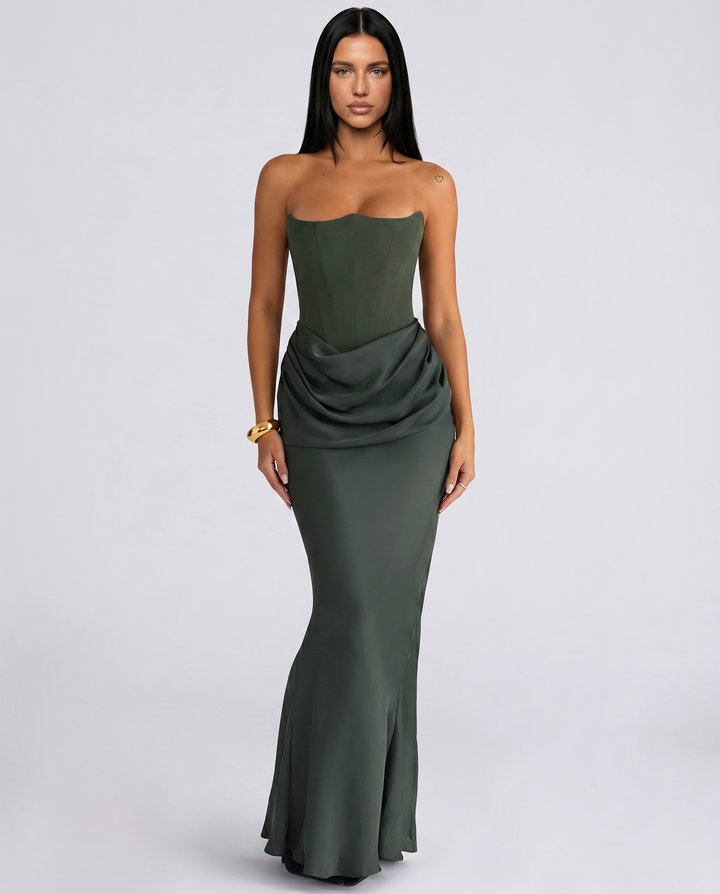 Woman wearing a strapless maxi dress with a draped waist on a plain background.