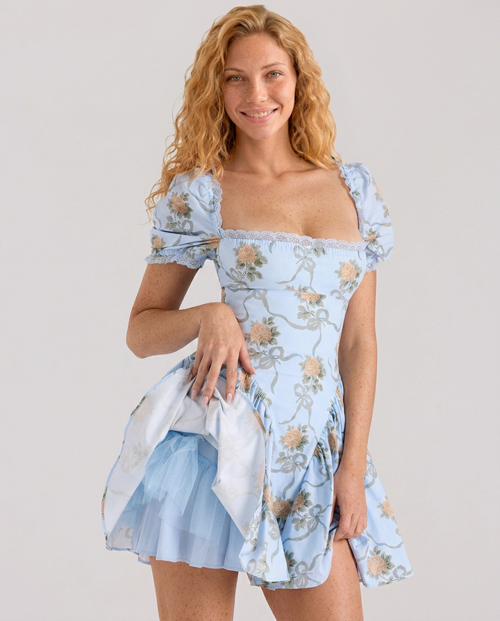 Female model wearing a short puff sleeve floral dress on a plain background.