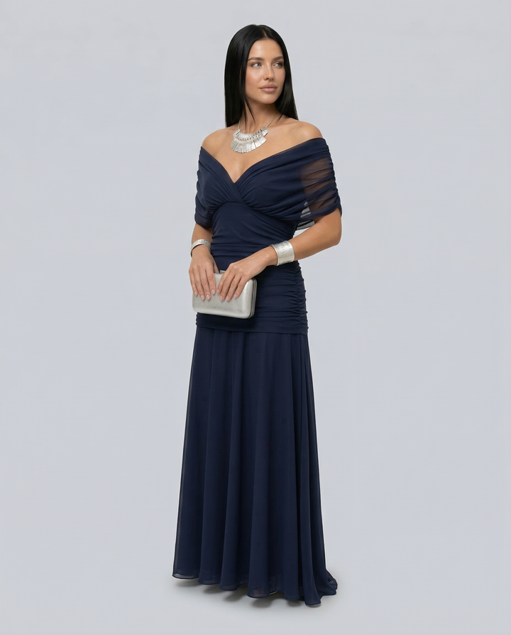 Female model wearing a graceful occasion dress for celebrations on a plain background.