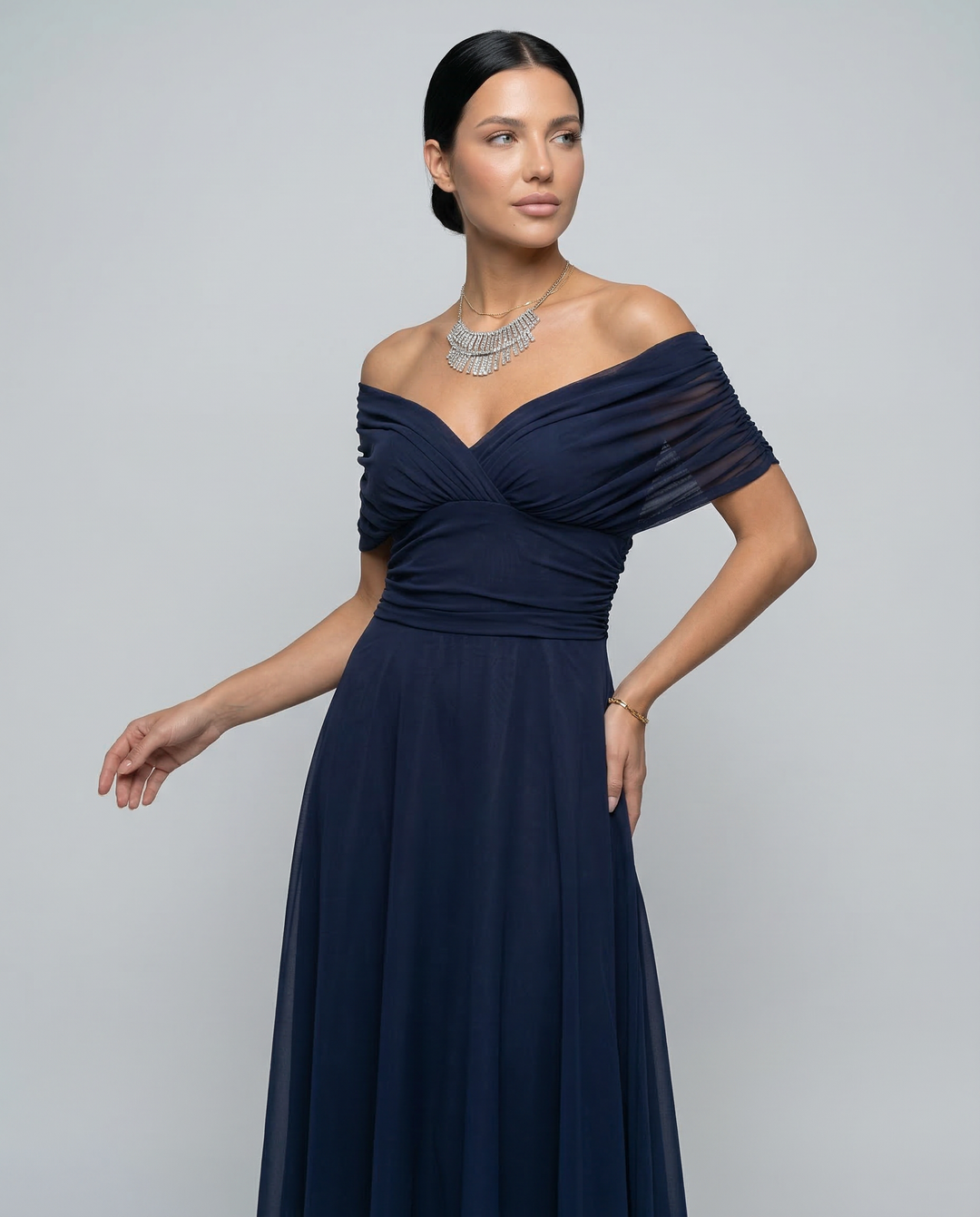 Female model displaying an elegant formal dress with relaxed drape on a plain background.