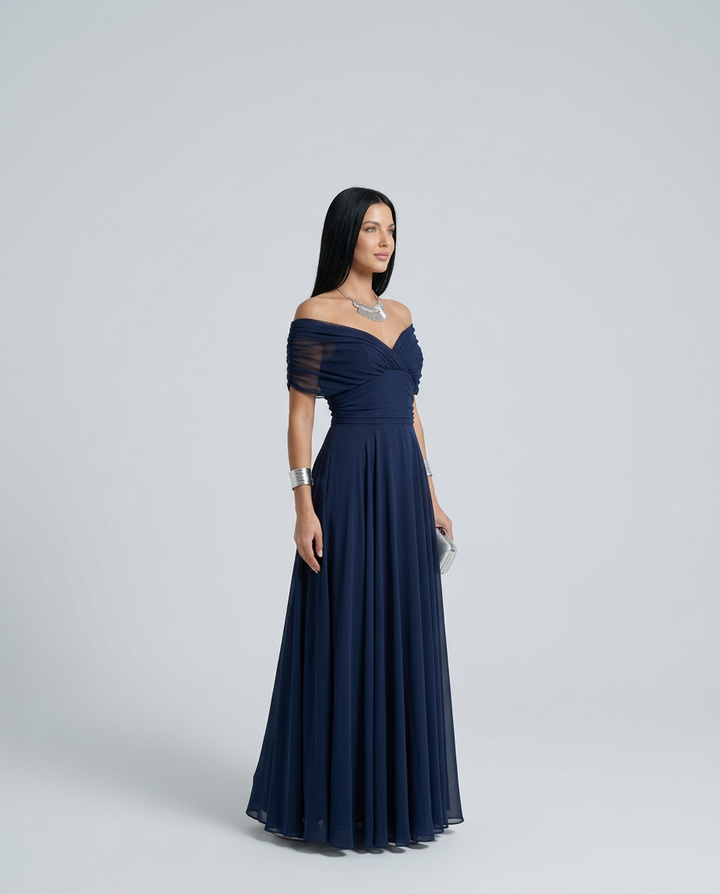 Woman styled in a flowing dress suited for dinners and receptions on a plain background.