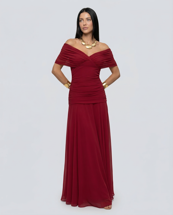 Woman in a polished formal outfit with a defined waist on a plain background.