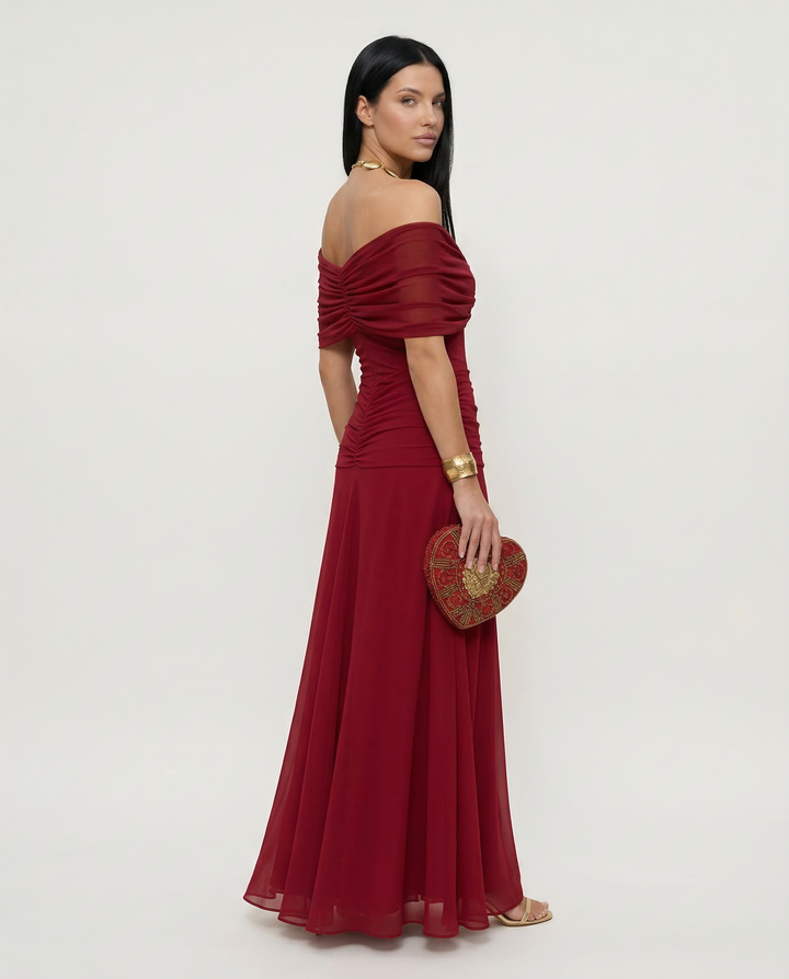 Female model in a flowing formal dress styled for evening events on a plain background.