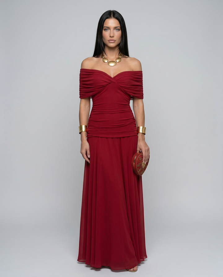 Woman wearing an elegant formal dress with a gathered waist on a plain background.